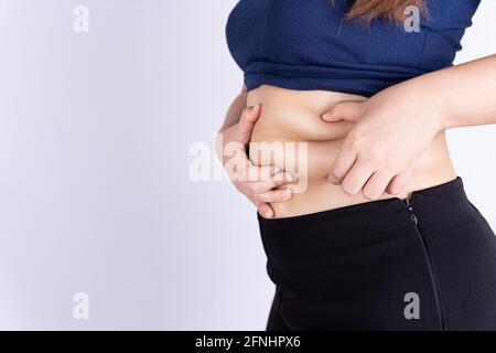 Fat woman holding excessive fat belly isolated grey background. Stock Photo