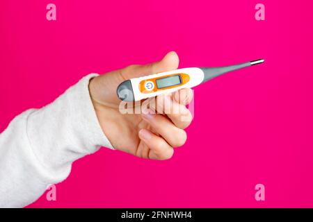 Electronic thermometer in a female hand. Thermometer for measuring body temperature. Stock Photo