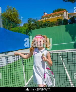 Posing tennis girl wearing a white sport dress in summer day. Playing tennis on the tennis court. High quality photo Stock Photo