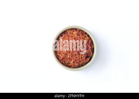 Saffron spices threads in heart shaped plate isolated on white background. Top view. Saffron flavor and coloring seasoning ingredient. Stock Photo