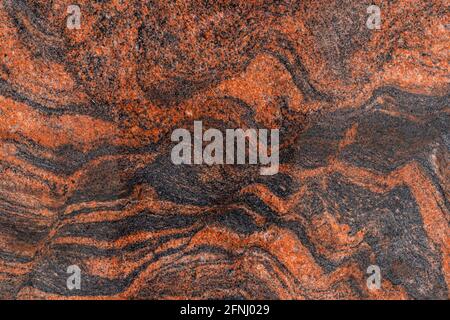 the texture of the stone is marble. Natural texture of polished stone brown color, black streaks. Stock Photo