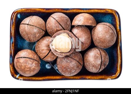 top view of sewn macadamia nuts with peeled seed in bowl cutout on white background Stock Photo