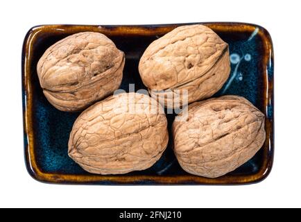 top view of several whole walnuts in bowl cutout on white background Stock Photo