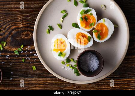 Halved hard boiled eggs on  plate on rustic wooden table, top view, keto diet breakfast Stock Photo