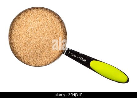 top view of demerara unrefined cane brown sugar in measuring cup cutout on white background Stock Photo