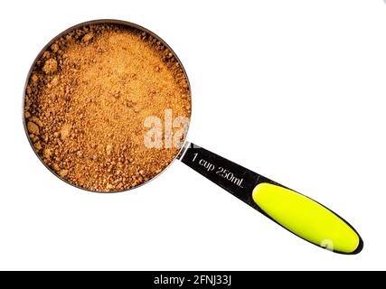 top view of granulated coconut blossom sugar in measuring cup cutout on white background Stock Photo