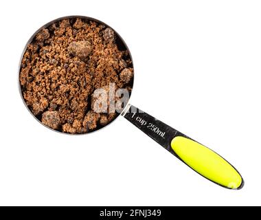 top view of dark brown muscovado sugar in measuring cup cutout on white background Stock Photo