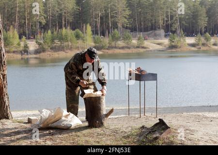 Man splitting firewood for preparation of barbecue in forest Stock Photo