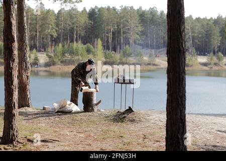 Man chopping wood for preparation of barbecue in forest Stock Photo