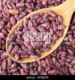 top view of red spotted pinto beans in wooden spoon closeup Stock Photo
