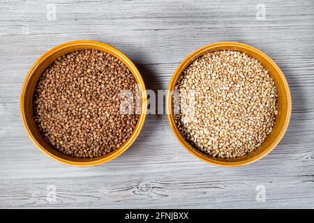 top view of roasted and green buckwheat in round ceramic bowls on gray wooden table Stock Photo