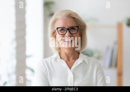 Headshot portrait of smiling senior businesswoman in office Stock Photo