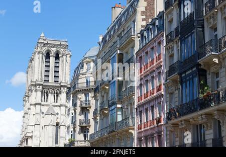 Traditional facades of French houses with typical balconies and windows with Notre Dame cathedral towers in the background. Paris. Stock Photo