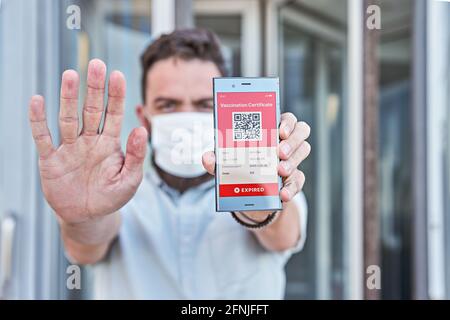 Man holding smartphone displaying on app mobile expired digital vaccination certificate for Covid-19. Immunity vaccine passport, green vaccination cer Stock Photo