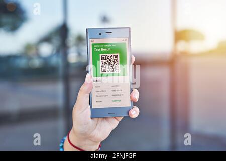 Hand woman holds smartphone displaying an app negative test result of covid-19. Express PCR test, digital result on mobile application Stock Photo