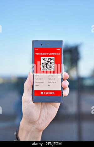 Hand man holds smartphone displaying an app mobile expired digital green vaccination certificate for Covid-19. Immunity vaccine passport, vaccination Stock Photo
