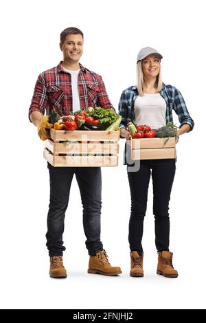 Full length portrait of a young man and woman holding crates full of vegetables isolated on white background Stock Photo