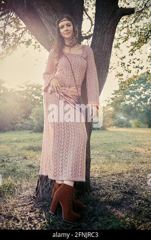 Outdoor portrait of the beautiful young boho (hippie) girl in grove (forest) at sunset time. Cute smiling woman stands at the tree Stock Photo
