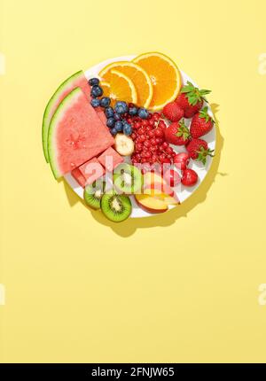 plate of various fruit and berries isolated on yellow background, top view Stock Photo