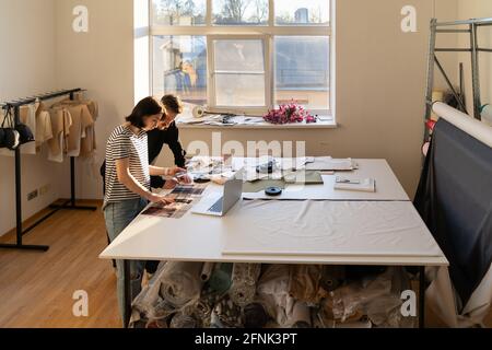 Two dressmaker work in studio with fabric samples for new collection. Team of designers in atelier Stock Photo