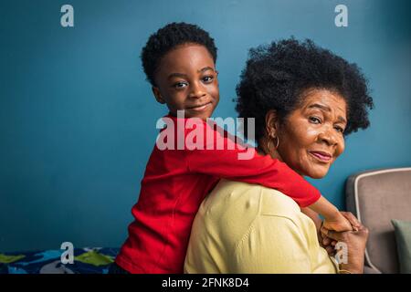 Side view portrait of cute boy with grandmother by blue wall at home Stock Photo