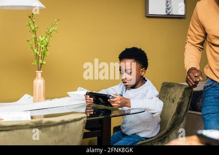 Boy using smart phone while sitting on chair at table Stock Photo
