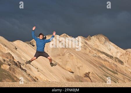 Teenager jumping in front of mountains of Landmannalaugar / Iceland Stock Photo