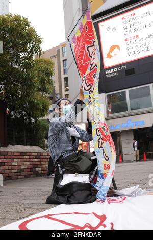 Tokyo, Japan. 17th May, 2021. A protester prepares a banner with 'Save the Tsukiji Market' during an anti Tokyo 2020 Olympic Games Rally in front of Shinbashi Station. The Tsukiji Market was moved from it's original location due to the Olympics.Around 30 to 40 protesters took to the streets calling for the cancelation of the Olympic Games this summer. They were accompanied by the same number of police officers. Protesters went from Shinbashi station through the Ginza district to the Head Office of the Organization Committee for the Games. Credit: SOPA Images Limited/Alamy Live News Stock Photo