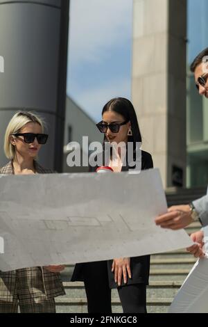 Three well suited business people are thinking about the plan while looking it Stock Photo