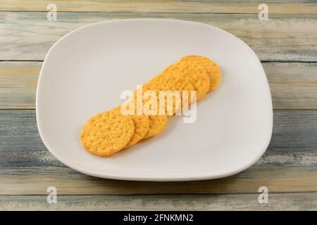 Cheese crackers in a row on white snack plate on table Stock Photo