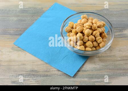 Turkish salted roasted chickpeas in glass snack bowl with blue napkin on table Stock Photo