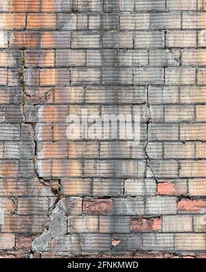 Unusual bricks with a grooved pattern in an old wall which is cracking and dirty and in need of repair to prevent collapse Stock Photo