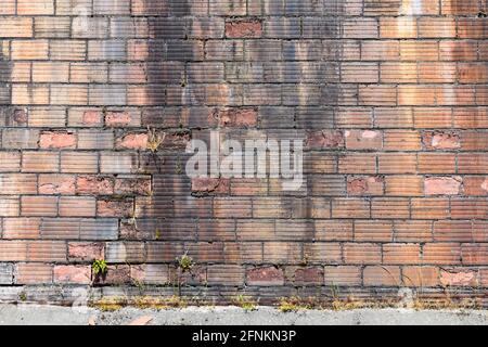 Unusual bricks with a grooved pattern in an old wall which is showing its age with pieces of the brick stretcher falling away with time Stock Photo