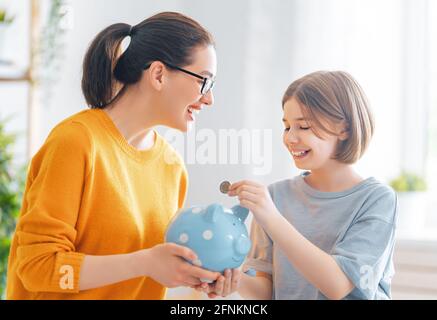 Woman and child sitting at desk with a piggy bank are calculating expenses, managing the family budget. Stock Photo