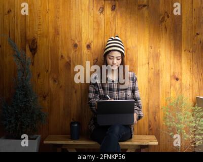 Young female freelancer woking on her project with tablet while sitting in comfortable workspace Stock Photo