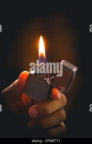 The man holding Brushed chrome lighter with windproof in the dark. Stock Photo