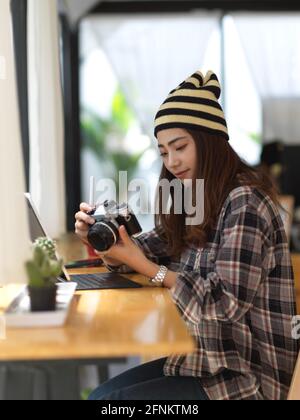Side view of female photographer holding camera while sitting in cafe Stock Photo