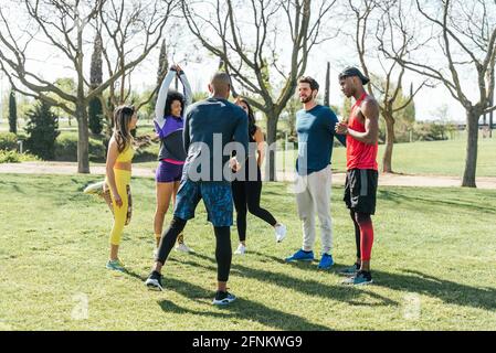 Group of friendly runners talking in a park before training. Stock Photo