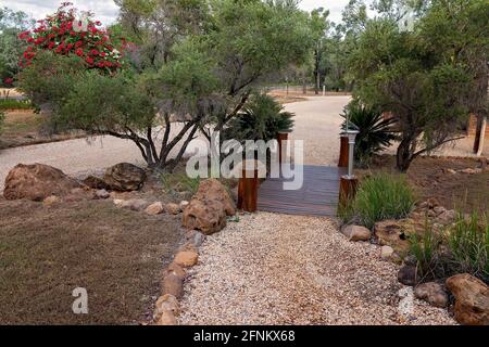 Pebble pathway and small timber bridge crossing in a country garden Stock Photo