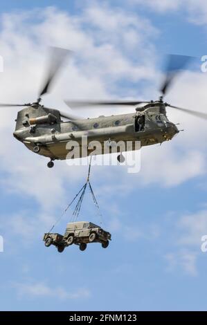 Royal Air Force, RAF, Boeing CH-47 Chinook medium lift helicopter with an underslung load of Land Rover car and trailer at Farnborough Airshow, UK Stock Photo