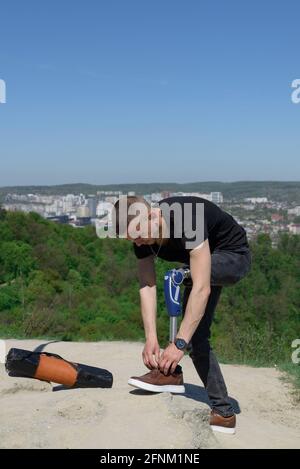 a man on a prosthetic leg travels the mountains. Dressed in black jeans and a T-shirt. Stock Photo