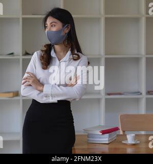 Portrait of female office worker wearing mask while standing in office room Stock Photo
