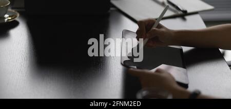 Side view of female hands using digital tablet with stylus pen on meeting table Stock Photo