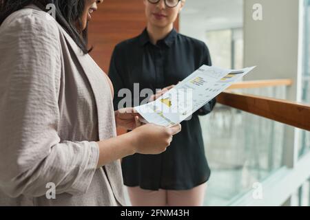 Close-up of business colleagues examining financial report and discussing it together standing at office Stock Photo