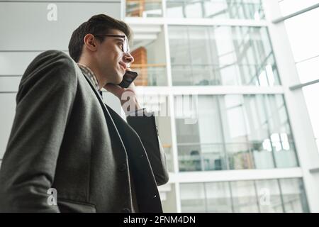 Young businessman in suit walking along the city and talking on mobile phone Stock Photo