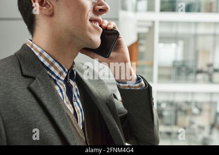 Close-up of young businessman talking on mobile phone while standing outdoors Stock Photo