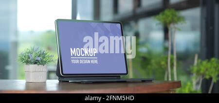 Cropped shot of portable workspace with laptop and plant pot on wooden table, clipping path Stock Photo