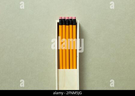 Yellow pencils in wooden pencil case on khaki background. top view, copy space Stock Photo