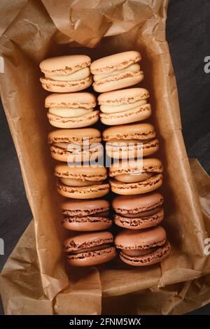 Brown, beige and cream colored French macarons with coffee, mocha, chocolate and vanilla flavor in tray with baking paper Stock Photo