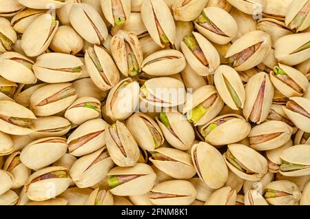 Roasted and salted pistachio seeds with shell, background, from above. Snack food, made from fruits of Pistacia vera. Stock Photo